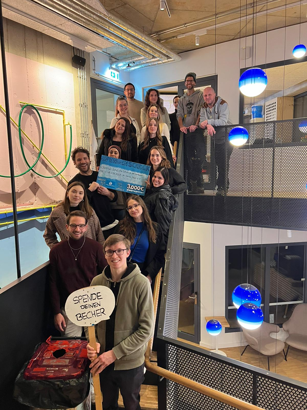 Viva con Agua. Zu sehen sind junge Menschen auf einer Treppe mit einem Gutschein.